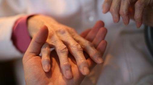 Holding elderly woman's hand in assisted living facility